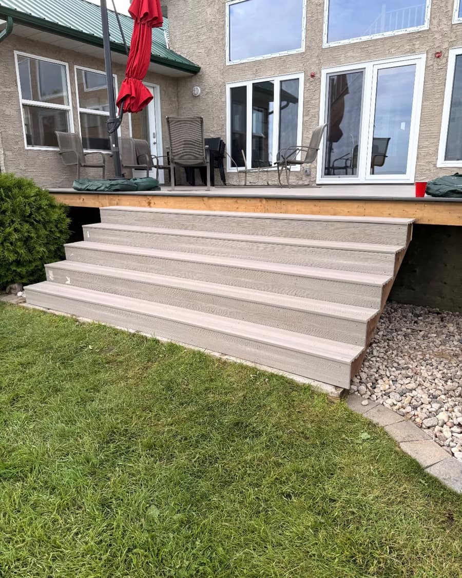 Finished composite stairs stepping down from a lakeside deck to the lawn.