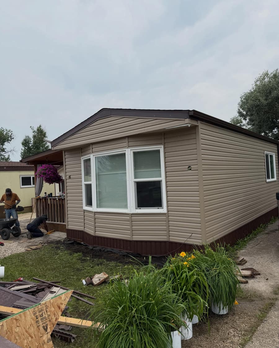 A full siding replacement partway through, with new horizontal panel going up over fresh wrap.