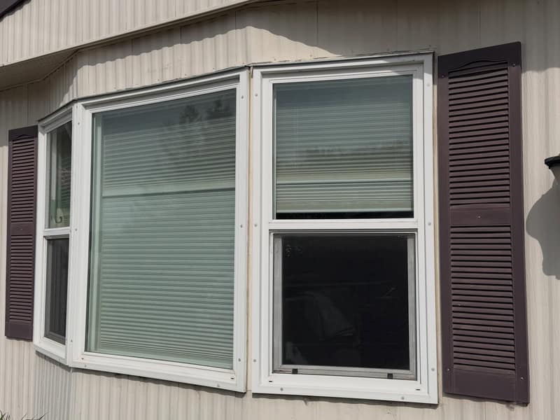 The original wall: tired vertical panel siding with failing trim and mismatched shutters.
